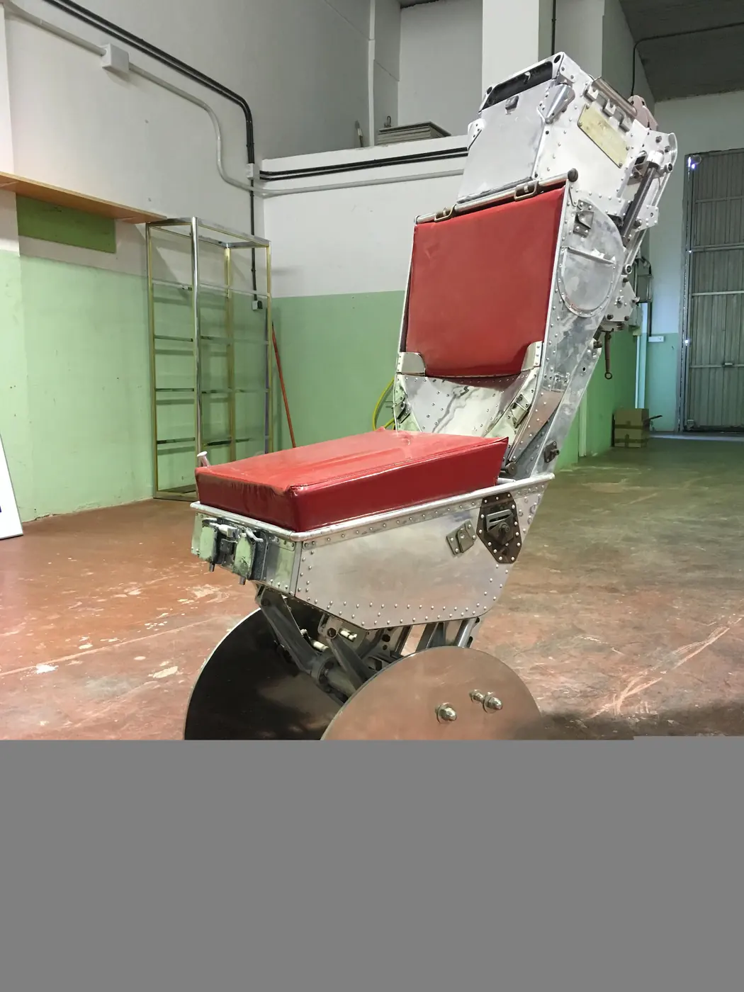 Asiento eyectable restaurado, con tapicería de cuero rojo y estructura de aluminio pulido