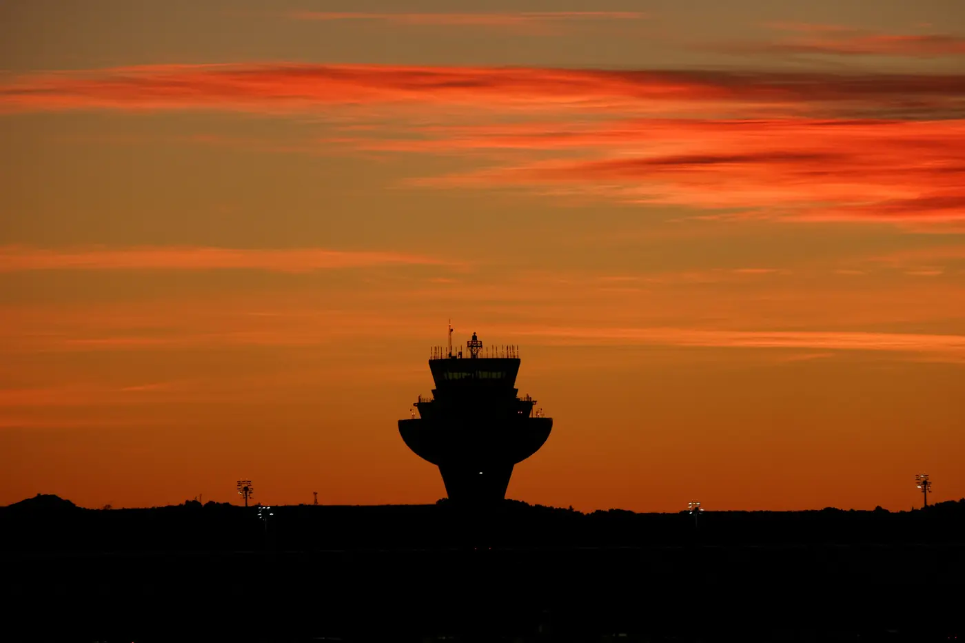 Silueta de una torre de control recortada contra un cielo rojo